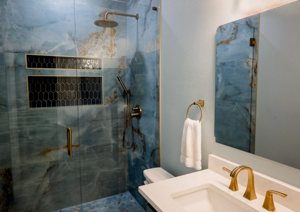 After: remodeled bathroom with walk-in shower, blue stone tile and brass fixtures in DFW