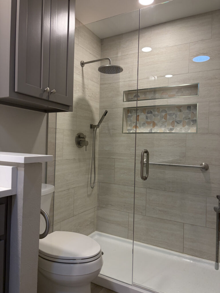 Bathroom remodeling in DFW: walk-in shower with wood-look tile, mosaic niche and glass door