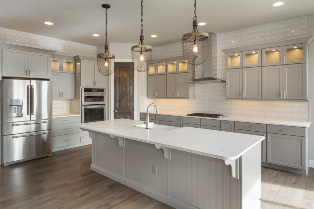Gray shaker kitchen with quartz island and pendant lights, kitchen remodeling by Heritage Remodelers serving Haslet, TX
