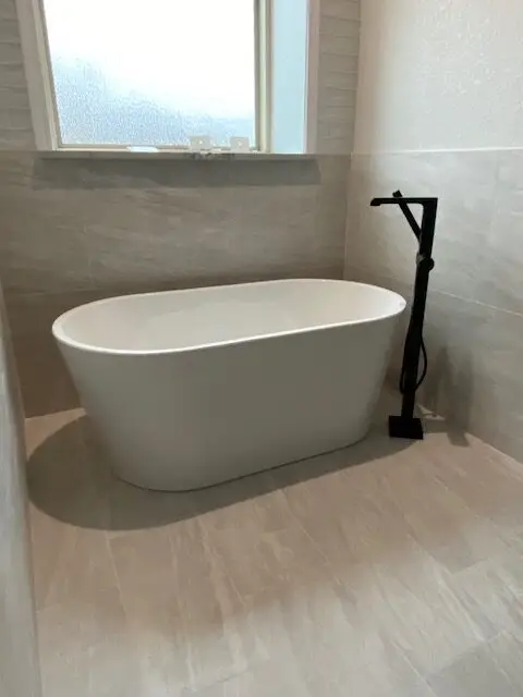 Freestanding soaking tub with floor-mounted black tub filler, bathroom remodel
