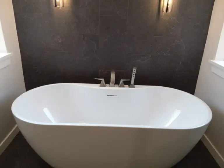 Freestanding tub against a dark accent wall with deck-mount faucet