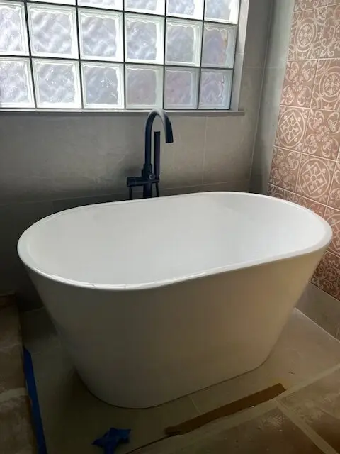 Freestanding tub installed beneath a glass block window, bathroom remodel
