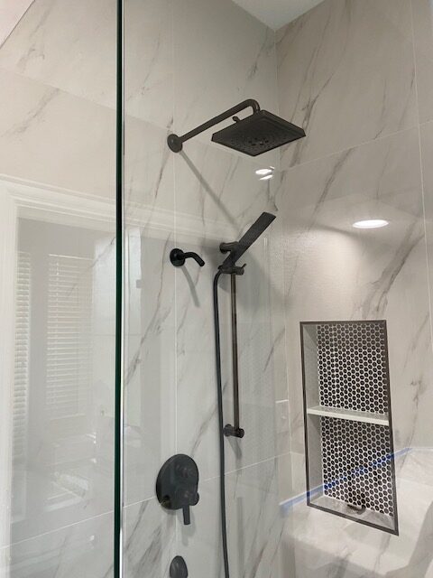 Walk-in shower with marble-look tile, matte black fixtures and recessed niche