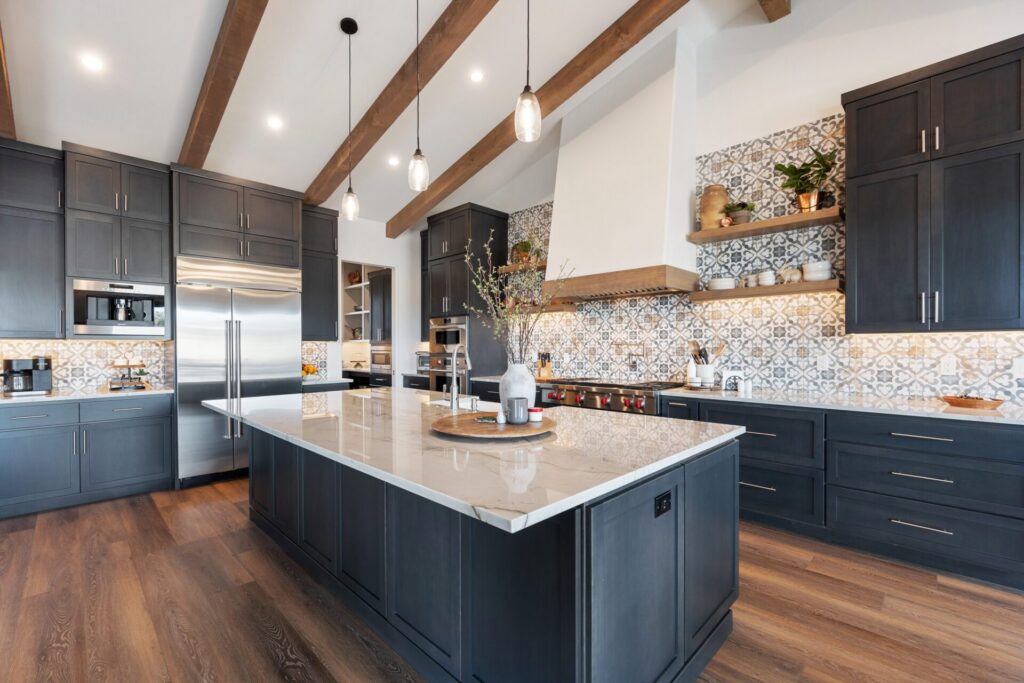 Navy kitchen island under a vaulted wood-beam ceiling with brass pendants, kitchen remodeling by Heritage Remodelers & Builders in DFW