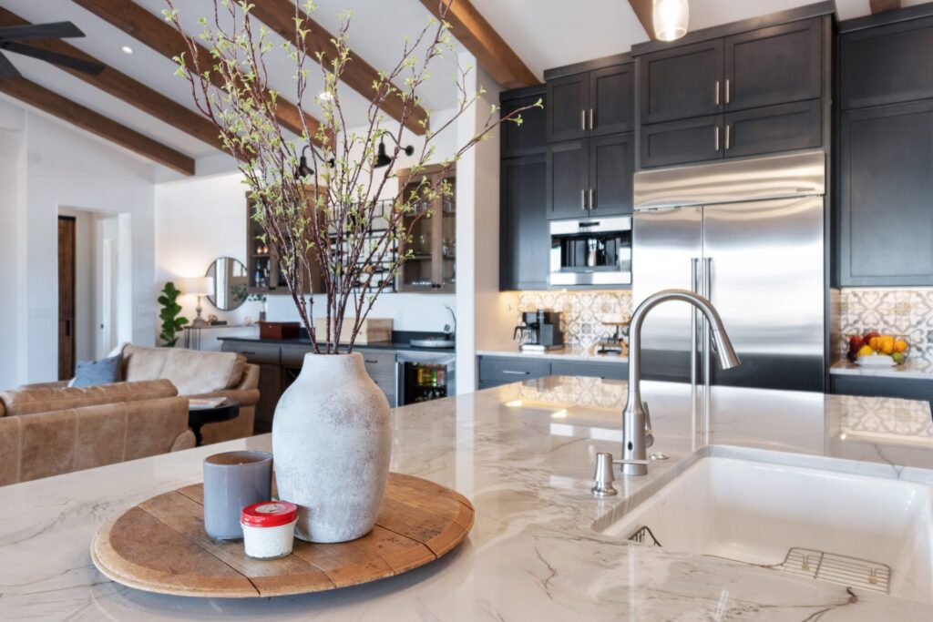 Quartz island with farmhouse sink and designer faucet in a dark-cabinet kitchen