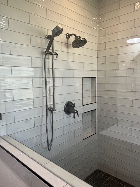 Subway tile shower with dual shower heads and recessed niche