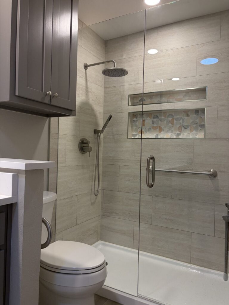 Bathroom remodeling in DFW: walk-in shower with wood-look tile, mosaic niche and glass door